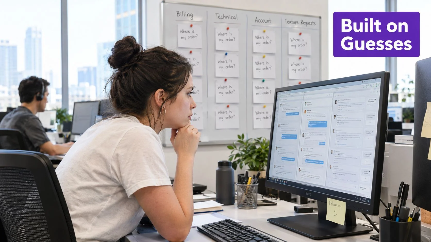A woman working at her desk in an office with a whiteboard full of FAQs behind her.
